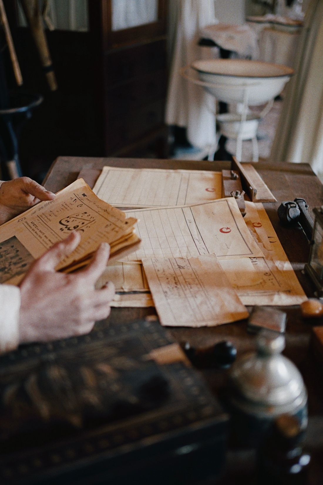 Hands sorting a stack of old papers on a wooden desk